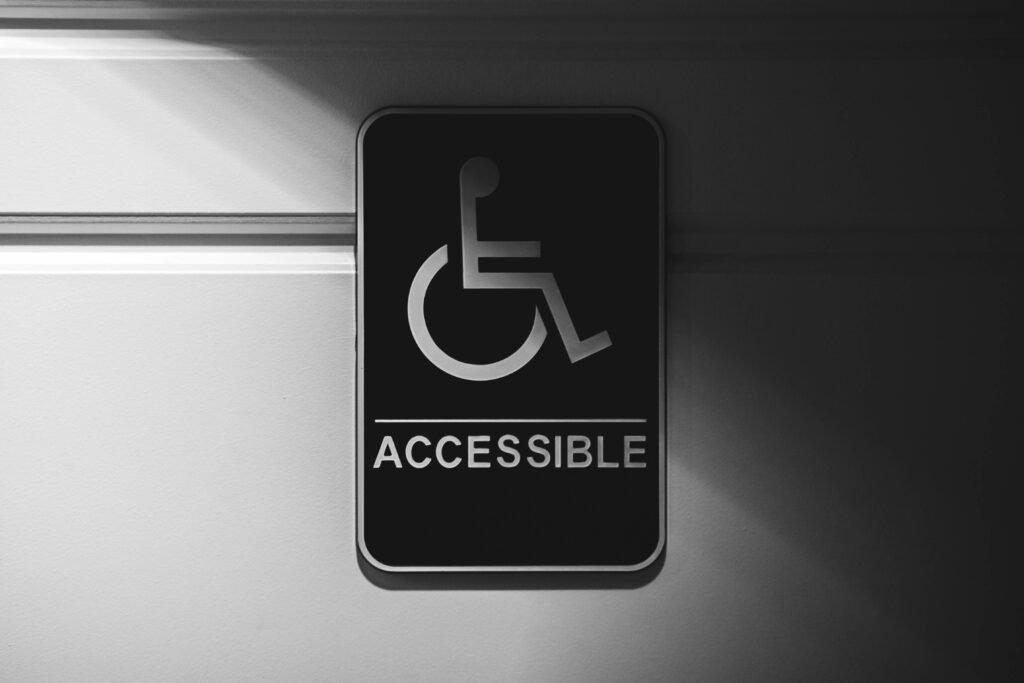 Black and white sign with wheelchair symbol and the word "ACCESSIBLE" on a textured wall.