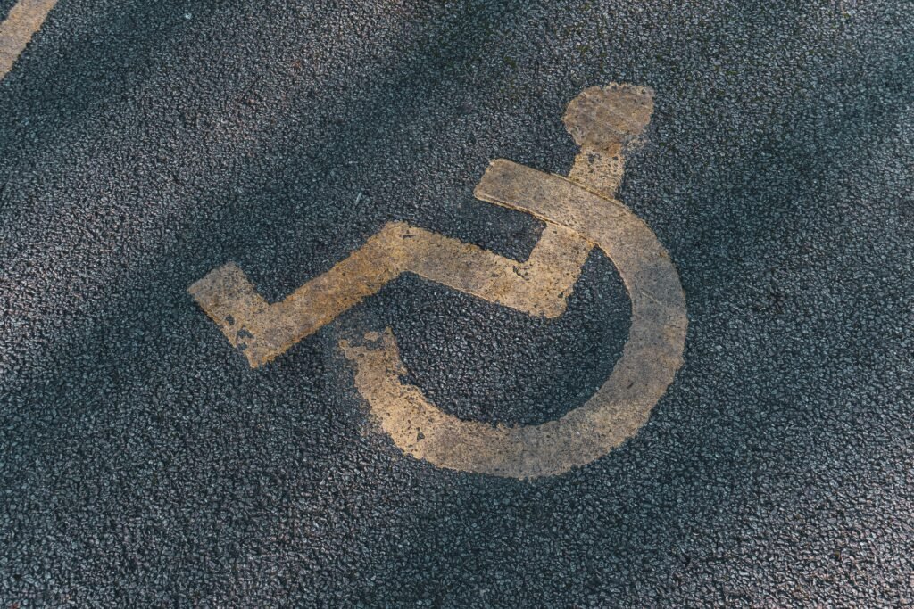 Yellow wheelchair symbol painted on asphalt.