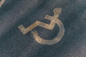 Yellow wheelchair symbol painted on asphalt.