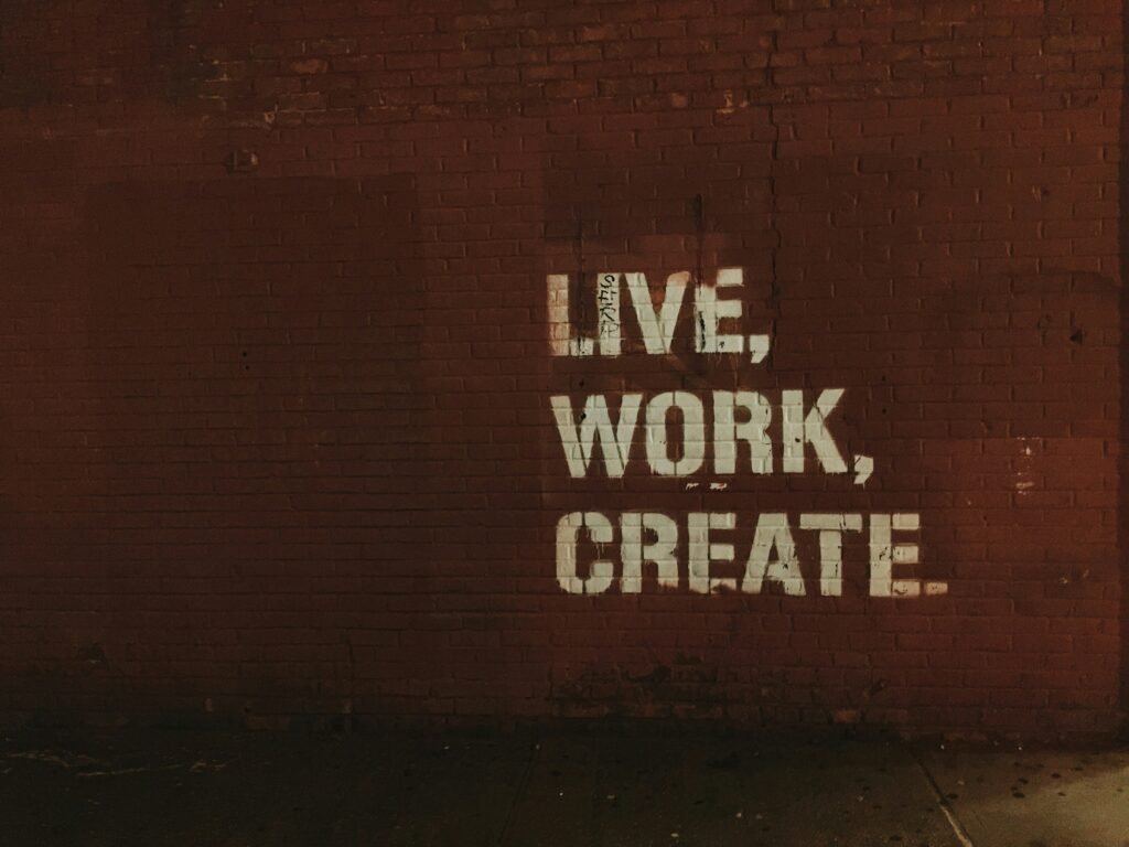 White stencil text on a brick wall reads "LIVE, WORK, CREATE.".