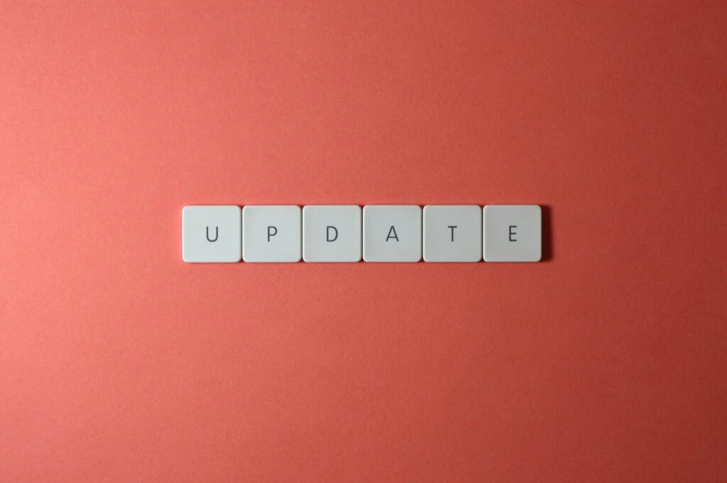 White tiles with black letters spell "UPDATE" on a coral background.