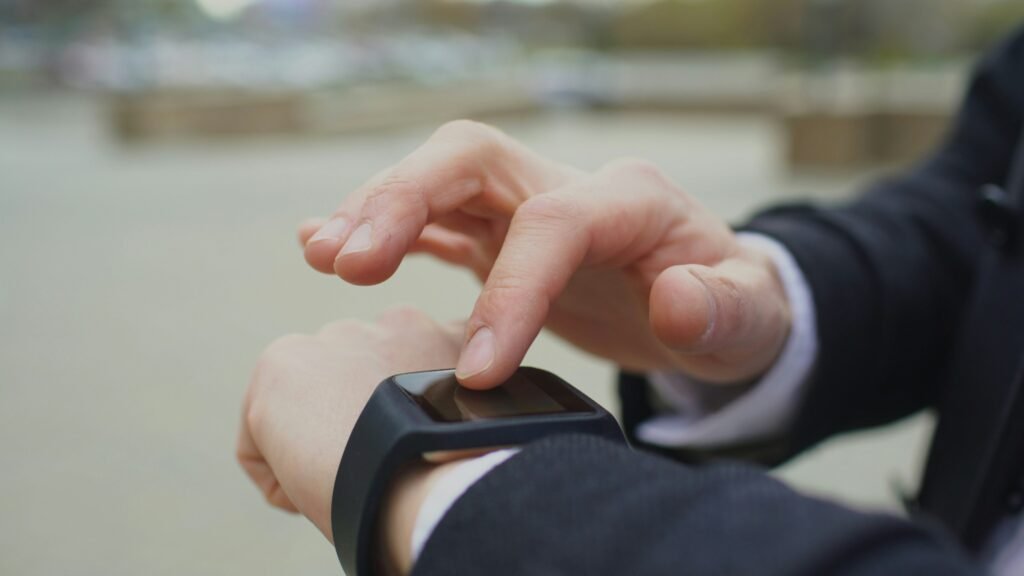 Person in a suit uses a smartwatch, touching the screen with a finger.