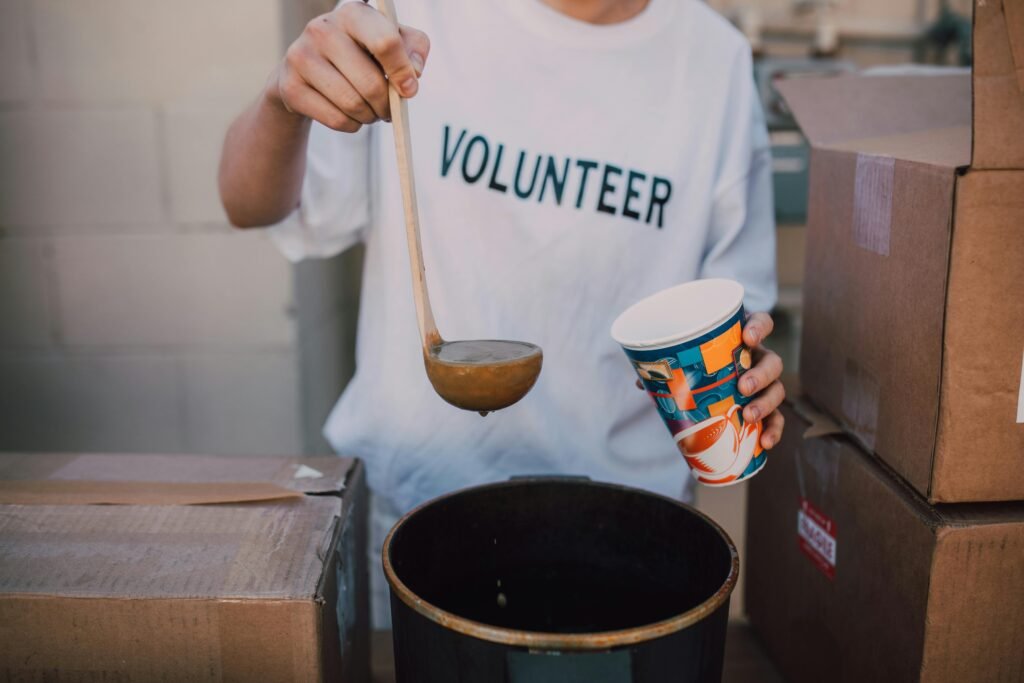 A volunteer ladles soup into a cup next to boxes, illustrating the importance of non profit seo