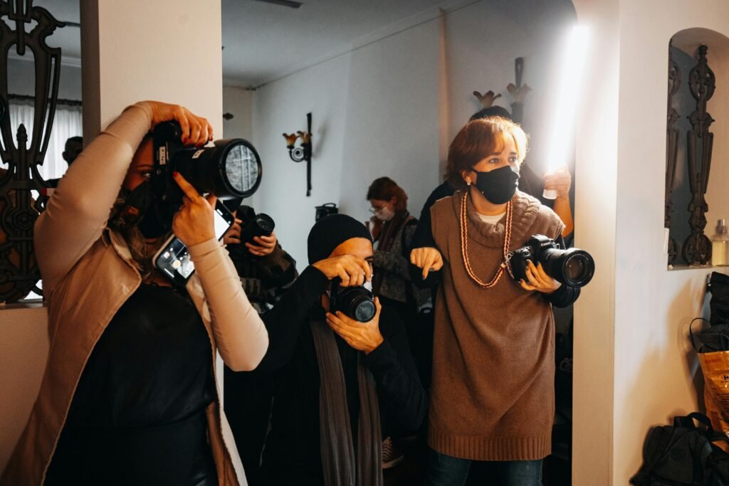 Photographers in a dimly lit room hold cameras and phones, possibly discussing photography seo