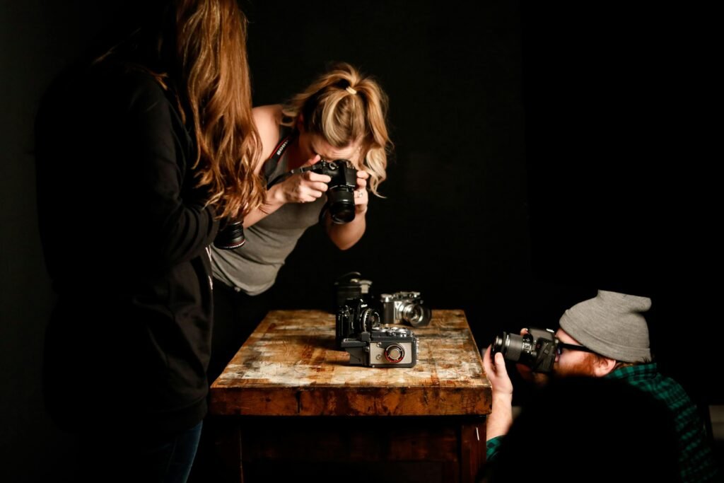 Three people focus on cameras on a wooden table, hinting at the importance of photography seo