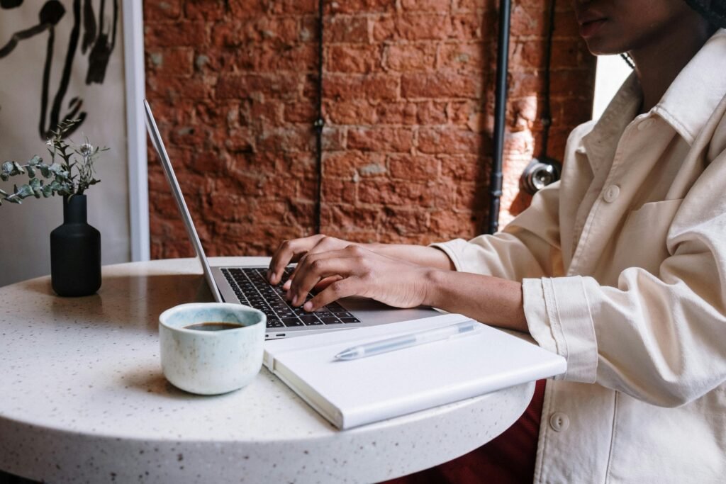A person types on a laptop next to a coffee cup and notebook, illustrating the importance of core web vitals images for SEO success