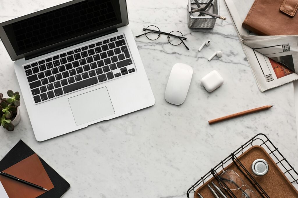 A laptop, mouse, earbuds, and glasses are arranged on a marble desk, illustrating how core web vitals images impact SEO success