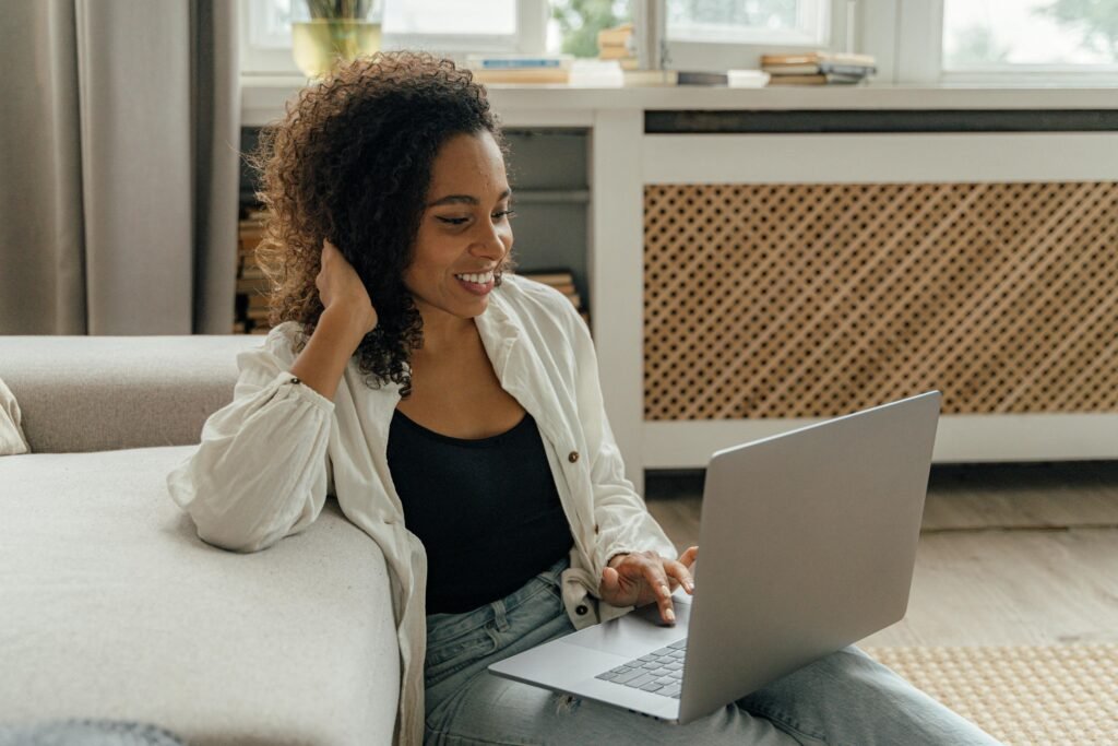A woman with curly hair smiles while working on a laptop, demonstrating ethical ai