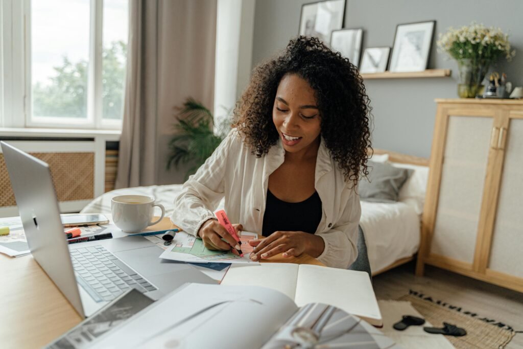 A woman with curly hair works at a desk with a laptop, papers, and a cup of coffee, demonstrating ethical ai